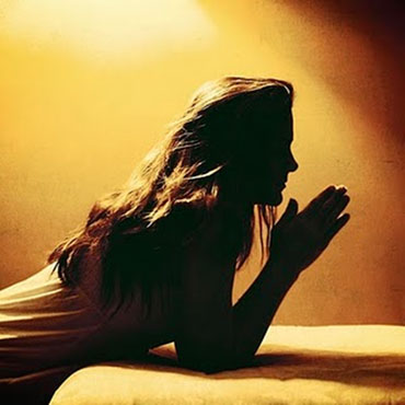 Женщина молится у кровати