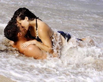 Девушка целует парня в море